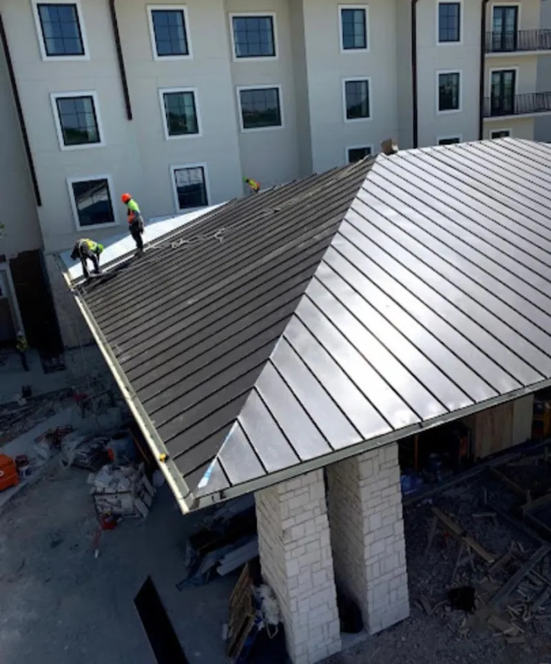 Crew installing standing seam metal roof panels on a commercial project in Wilson